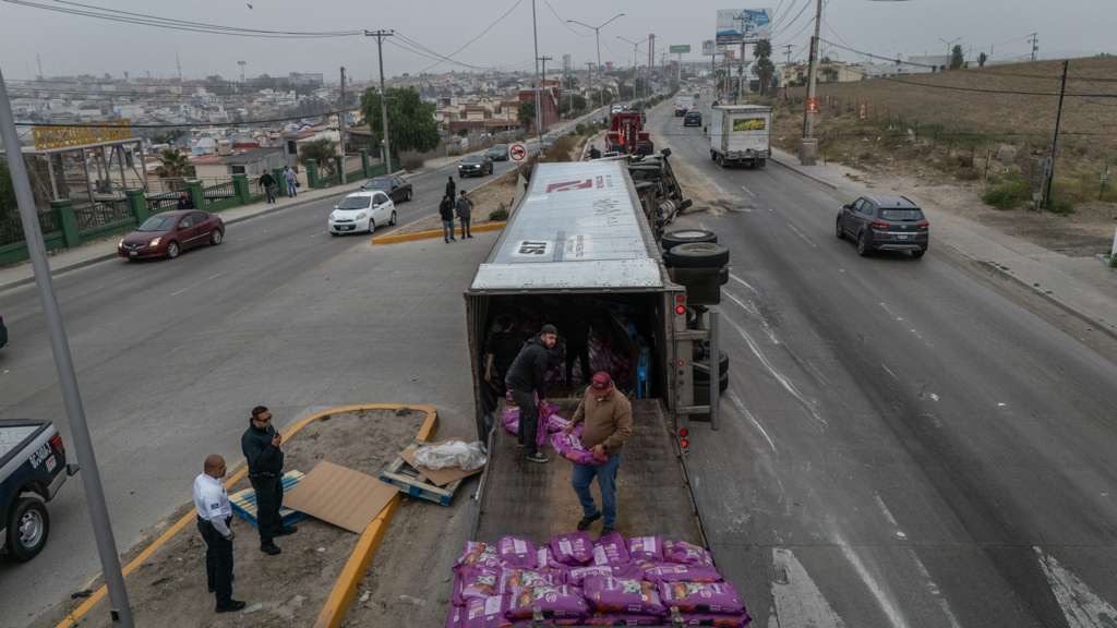 Personas bajando las croquetas del camión volcado.