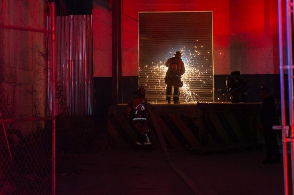 Elementos de bomberos intentando ingresar a la paquetería donde se originó el conato de incendio.