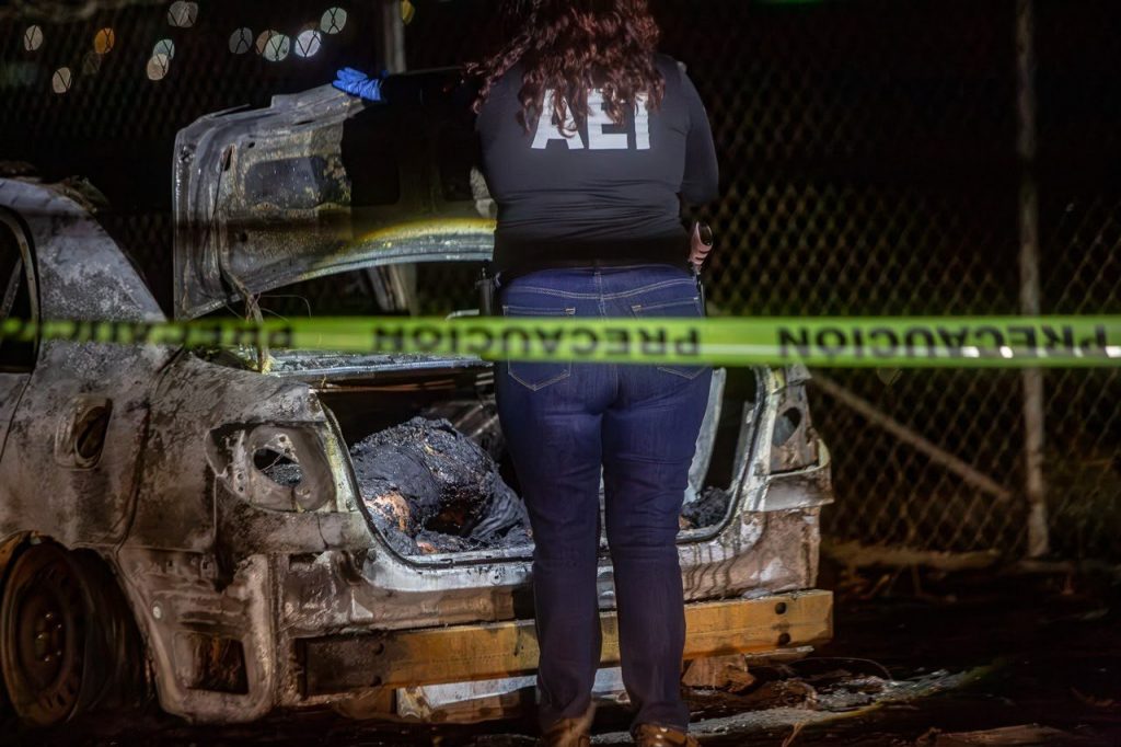 Autoridades estatales procesando la escena del auto calcinado y los cuerpos en la cajuela.